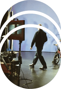 A director walks across set while a BMX rider sits on his bike in front of an LED wall