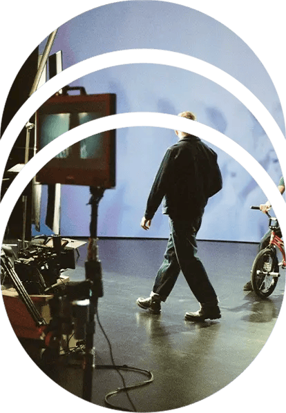 A director walks across set while a BMX rider sits on his bike in front of an LED wall