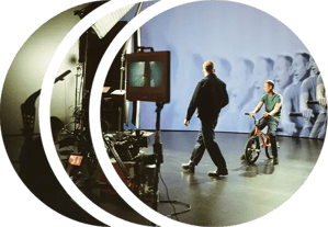 A director walks across set while a BMX rider sits on his bike in front of an LED wall