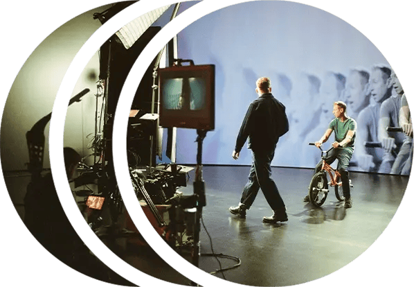 A director walks across set while a BMX rider sits on his bike in front of an LED wall
