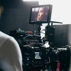 A closeup of someone is shown on a SmallHD monitor attached to a RED cinema camera