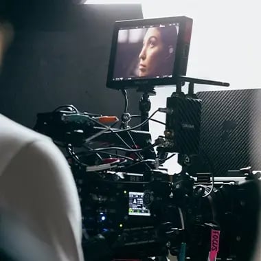 A closeup of someone is shown on a SmallHD monitor attached to a RED cinema camera