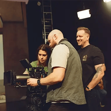 FIlm Crew and Cinematographer gathered around a RED cinema camera while on set
