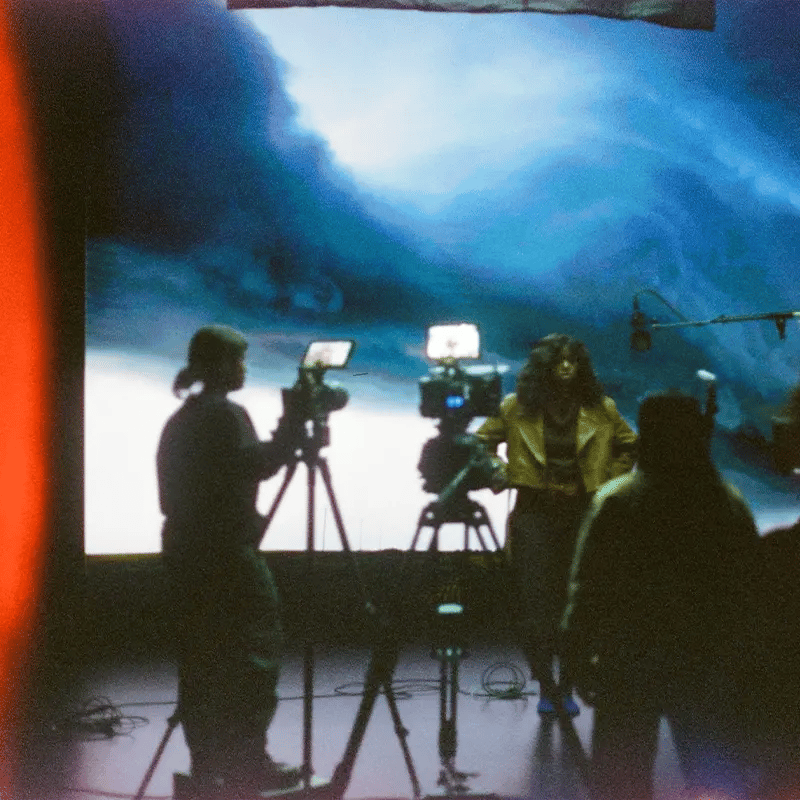 A film crew filming a musician in front of 2d video loop plates on an LED wall