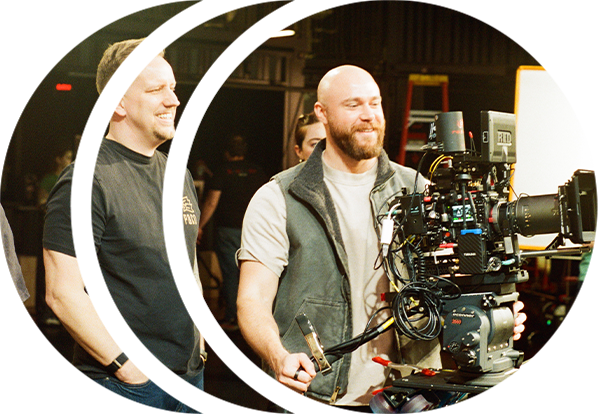 A director watches as a cinematographer operates a RED cinema camera with a REDSPY camera tracker on it