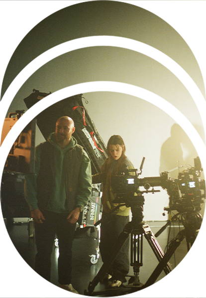 Film crew stands next to two RED cinema cameras in a virtual production studio in front of the LED wall