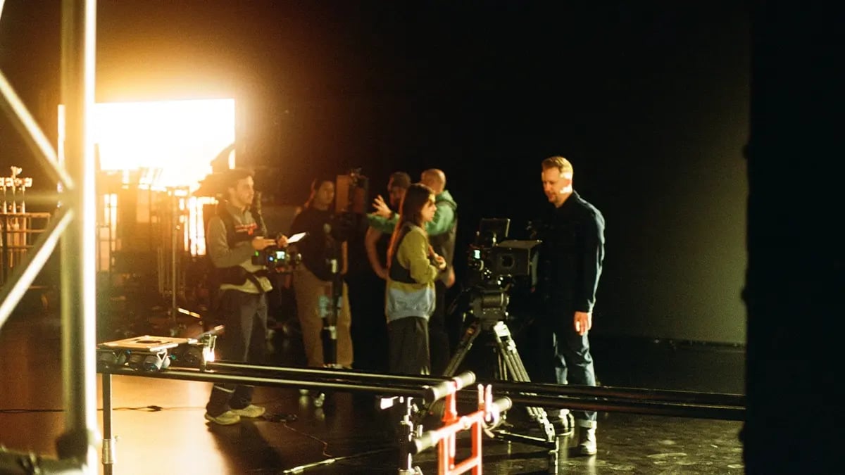 A film crew is standing on a film set around a dana dolly