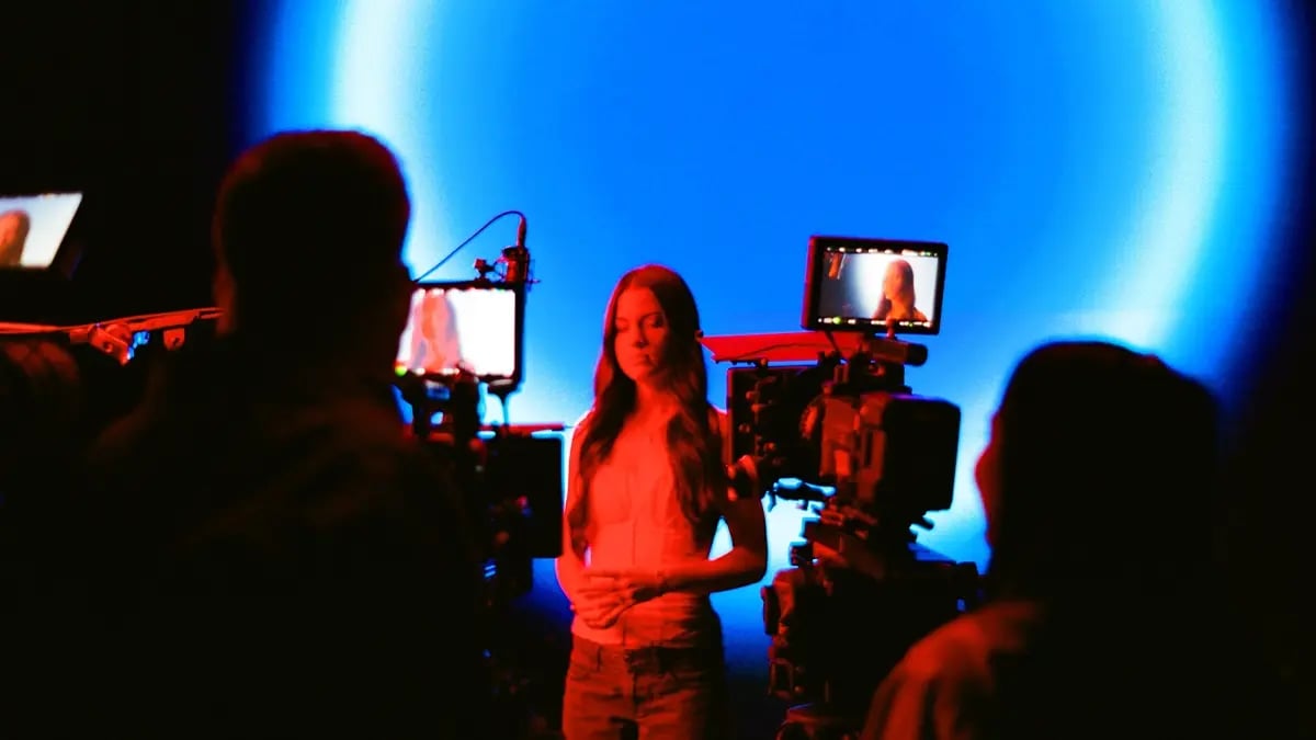 A director and cinematographer filming a singer performing in front of an LED wall filming a music video