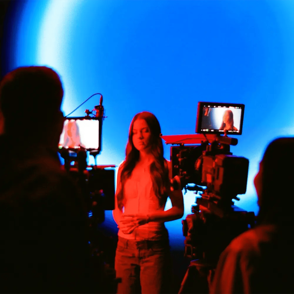 A musician is filmed by camera crew operating RED cinema cameras while singing in front of an LED wall for a music video