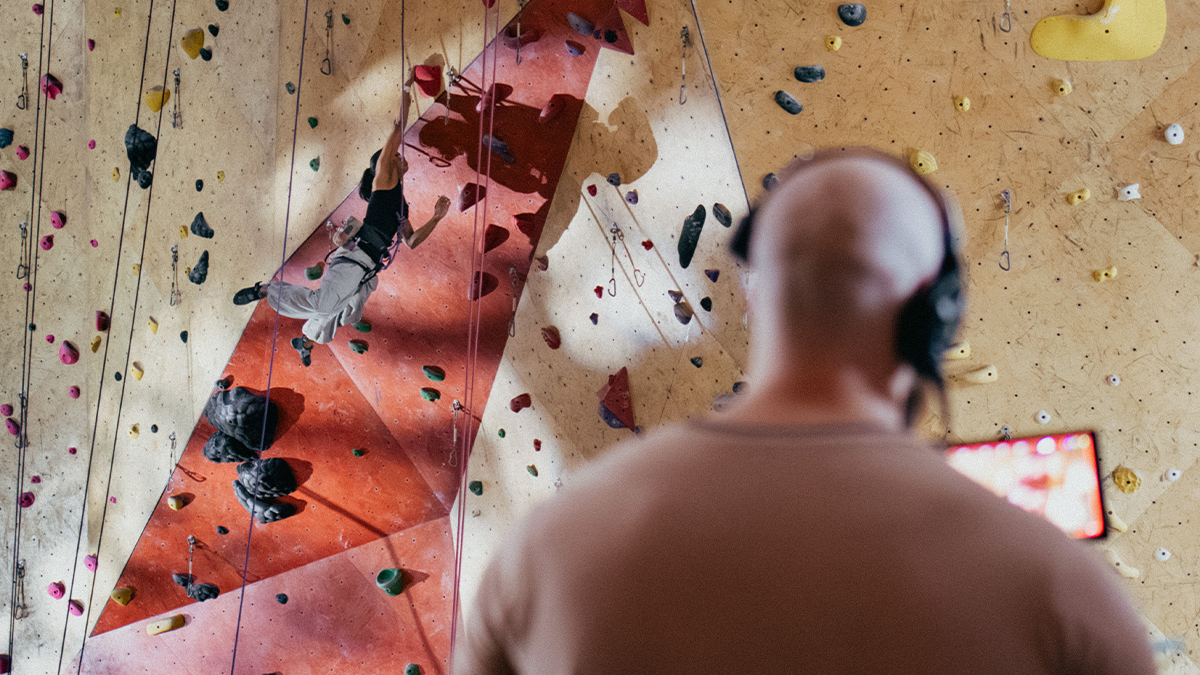 A cinematographer captures a rock climber ascending a wall